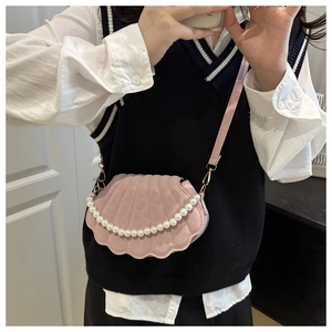 Pink shell-shaped crossbody bag featuring a decorative pearl chain on a female model