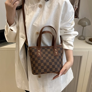Brown checkerboard tote bag with gold rivets and leather strap in minimalist setting