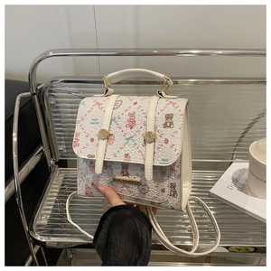 Detailed view of mini white backpack with floral bear prints and golden metal plaque