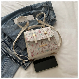 Macro detail of white mini backpack featuring cute bear print and textured floral fabric