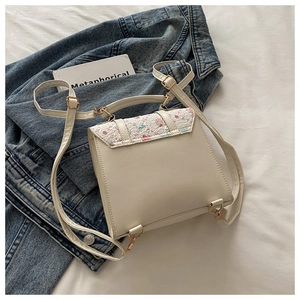 Detailed shot of floral embroidery and gold ring buckle on cream white leather backpack