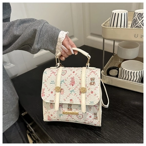 Detailed close-up of a sweet cartoon bear printed handbag with gold metal logo buckle