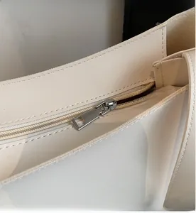 Close-up of smooth silver metal zipper on cream white faux leather tote bag