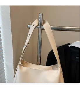 Detail of the reinforced cream tote bag strap showing premium stitching and hardware