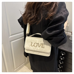 Détail du sac à bandoulière matelassé crème avec lettres LOVE dorées et garnitures