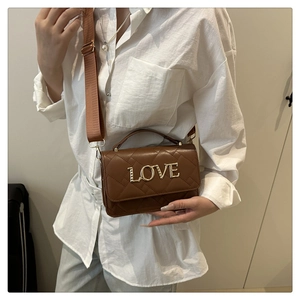 Close-up of brown quilted crossbody bag featuring gold LOVE logo and wide nylon strap