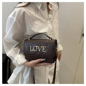Detailed view of chocolate quilted crossbody bag with golden LOVE lettering and slim strap