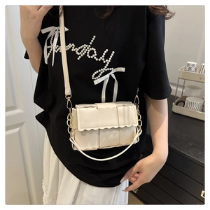 Detail of off-white woven crossbody bag with scalloped edge and golden chain strap