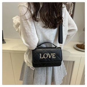 Rear view of model carrying a black quilted crossbody bag with gold LOVE lettering