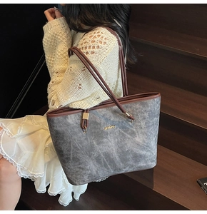 Dettaglio borsa tote grigia con manici in pelle marrone indossata da modella in pizzo