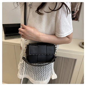 Détail du sac tressé noir en cuir avec bord festonné et bandoulière en chaîne