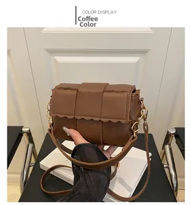 Détail d'un sac bandoulière marron tressé avec bords festonnés et bandoulière chaîne