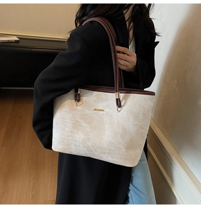 Detail of the minimalist off-white tote bag with dark brown straps and golden logo