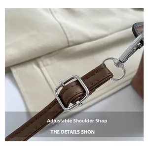 Detalle de correa ajustable de cuero marrón con hebilla de metal plateado en un bolso