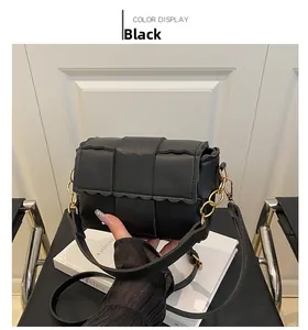 Détail du sac à bandoulière tressé noir avec bords ondulés et sangle en chaîne