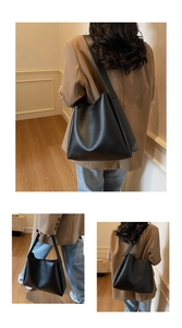 Detail view of large black matte leather tote bag worn by a model in a home setting
