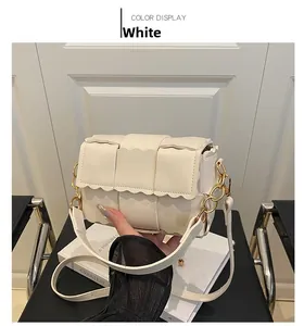 Détail du sac à bandoulière blanc tissé avec bords ondulés et sangle à chaîne dorée