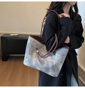 Dettaglio della borsa tote in tela lavata con manici in pelle marrone e logo dorato