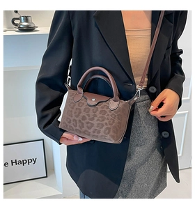 Leopard print nylon crossbody bag with brown leather accents shown in a lifestyle setting
