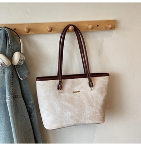 Detail of a beige tote bag with marble texture and JINGPIN logo on a wooden hanger