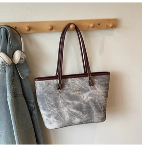 Detail of faux leather tote bag featuring marble pattern and gold metal brand logo