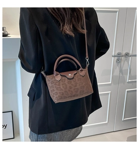 Detailed view of leopard print mini crossbody bag shown on a model in black blazer
