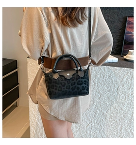 Close-up of leopard print handbag with leather handles and silver hardware on a model