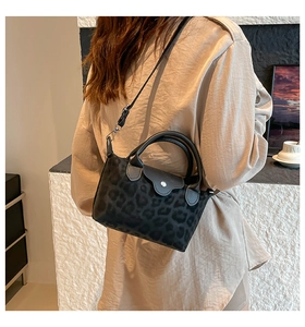 Detalle del bolso con estampado de leopardo gris, asa de cuero y cierre de botón metálico