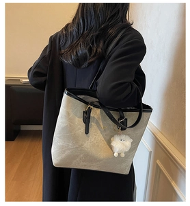 Close-up of contrast grey tote bag with black trim and a white plush toy pendant