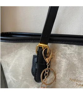 Detail of high-gloss gold hardware and marble-textured grey leather on a tote bag