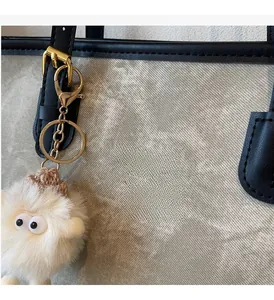 Detail of canvas tote bag with black leather trim and cute furry monster keychain