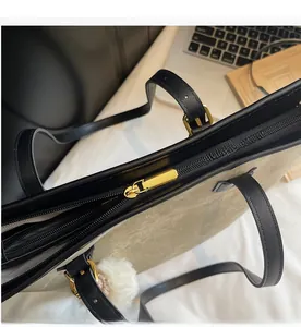 Detail of smooth gold zipper and black leather handle on olive tote bag