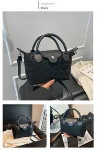 Detail of black leopard print handbag featuring leather handles and silver metal snap closure