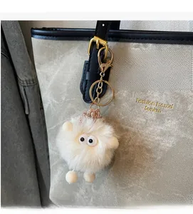 Close-up of a white plush ball charm with cute eye details on a luxury tote bag