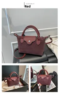 Detail view of burgundy leather handbag showing strap, handle and dumpling bag shape