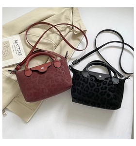 Detail of red and black leopard print handbags with leather flaps on a white background