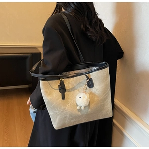 Close-up of beige marble pattern tote bag with black trim and white plush lamb charm