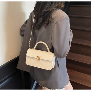 Model showcasing off-white crocodile embossed crossbody bag with gold buckle on stairs