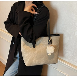 Detail of vintage beige marble texture tote bag with plush sheep charm and gold text