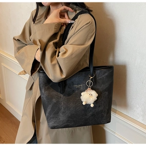 Detail of stone-washed grey tote bag with fluffy pendant and fashion print on trench coat