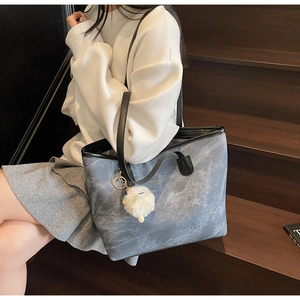 Close-up of marble texture tote bag with plush ball charm on high-quality fabric