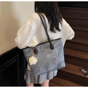 Detail of color-block tote bag with marble pattern, shoulder strap, and plush sheep charm