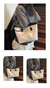 Detail of white tote bag with black trim, leather texture, and cute plush charm detail