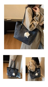 Detail of grey tote bag with leather straps, textured finish and cute plush lamb charm