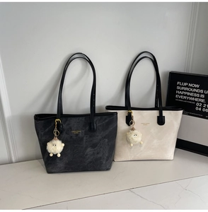 Detail of contrast color tote bags in dark grey and white with fuzzy monster charms