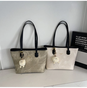 Close-up of contrast tote bags in olive and cream with leather straps and sheep charms