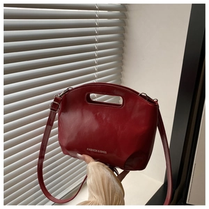 Macro shot of glossy red faux leather handbag with cutout handle and brand lettering