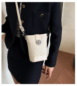 Detail of cream woven leather bucket bag with silver lock and adjustable shoulder strap