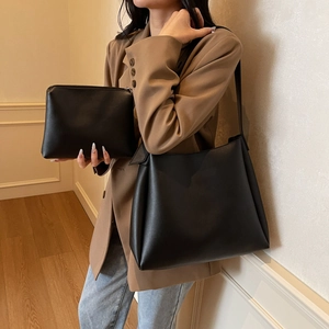 Minimalist black faux leather tote bag with matching inner pouch shown on shoulder
