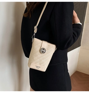 Detail of woven texture and metal twist lock on a minimalist crossbody bucket bag